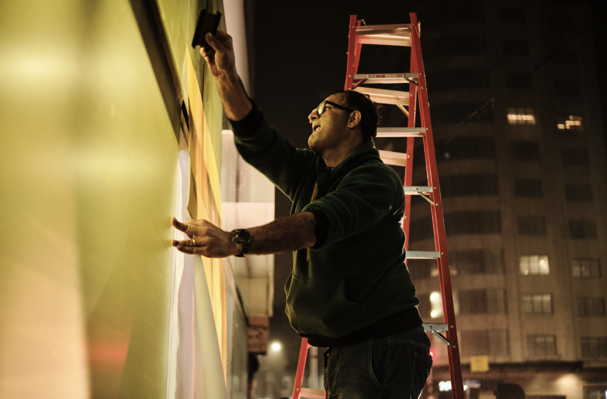Instalador aplicando acabamento na fachada durante a noite
